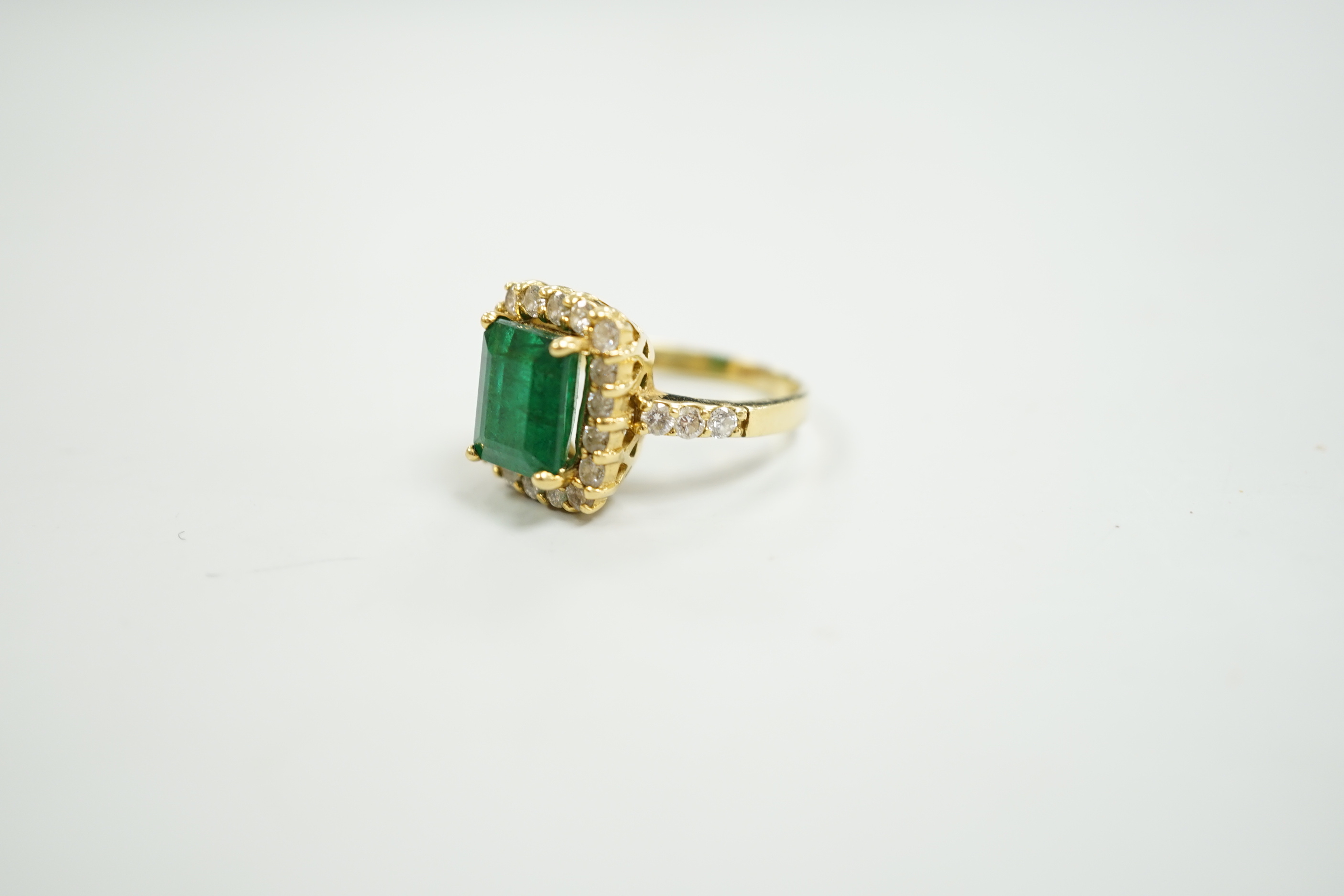 A modern 18ct gold and single stone emerald set dress ring, with diamond set border and shoulders, size L, gross weight 6.5 grams, with accompanying Beverley Hills Gemological Laboratory appraisal certificate date 18/11.